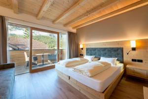 a bedroom with a large bed and a large window at Hotel Cavallino in Badia