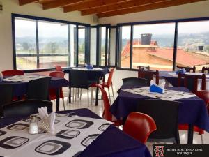 a restaurant with blue tables and chairs and windows at Hotel Hortensia Real in Paipa