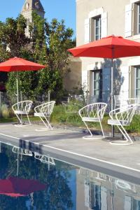 a group of chairs and umbrellas next to a pool at Le Général d'Elbée Hotel & Spa - Teritoria in Noirmoutier-en-l'lle