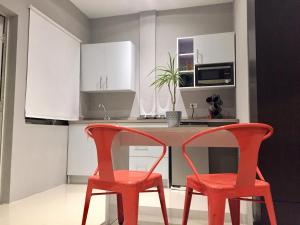 two red chairs in a kitchen with white cabinets at Brown Studio Apartment in Palm-Eagle Beach