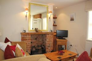 ein Wohnzimmer mit einem Kamin und einem Spiegel in der Unterkunft Seaside Fisherman Cottage Aldeburgh in Aldeburgh