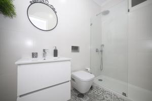 een witte badkamer met een toilet en een spiegel bij Casa do Zézêras in Nazaré +69 foto's