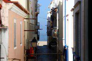 een steegje tussen gebouwen met de oceaan op de achtergrond bij Casa do Zézêras in Nazaré
