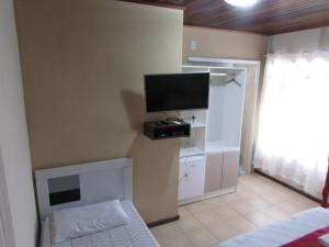 a bedroom with a tv on the wall at Pousada Sonho Meu in Penha