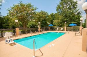 einen Pool in einem Resort mit Stühlen und Sonnenschirmen in der Unterkunft Baymont by Wyndham Jackson/Ridgeland in Jackson