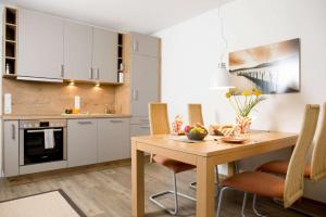 eine Küche und ein Esszimmer mit einem Holztisch und Stühlen in der Unterkunft Villa Meeresrauschen Wohnung 14 in Pelzerhaken