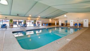 a large swimming pool with blue chairs and tables at Best Western Plus Keene Hotel in Keene