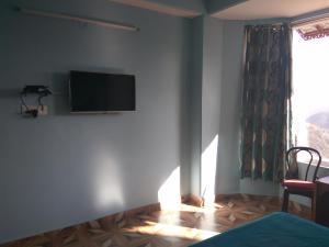 um quarto com uma televisão de ecrã plano na parede em Peaceful & scenic Homestay in Shoghi-Shimla em Shimla