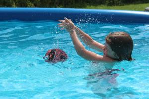 a young girl playing with a turtle in a swimming pool at Pension Pilsachhof in Arriach