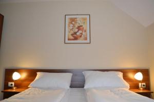 een slaapkamer met 2 bedden met witte lakens en 2 lampen bij Casa Retezat in Rîu de Mori