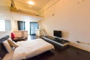 a bedroom with a bed and a television and a staircase at L Hotspring B&B in Jiaoxi