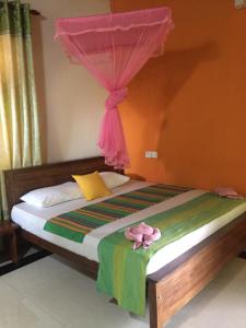 a bedroom with a bed with a pink curtain at Bee Nest Bed & Breakfast in Negombo