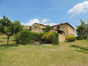 una casa vieja en un campo al lado de un edificio en Agriturismo Fonte Senesi, en Monticchiello