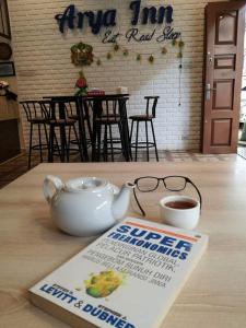 a tea pot and glasses on a table with a book at Arya Inn in Pematangsiantar