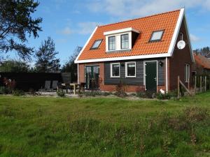una casa con techo naranja y puerta verde en Vakantiehuis het Neerland, en Biggekerke