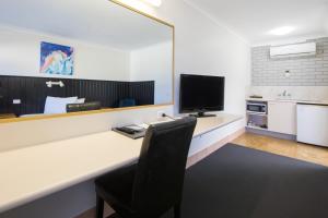a kitchen with a table and chairs and a refrigerator at Caboolture Motel in Caboolture