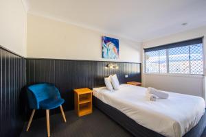 a hotel room with a bed and a blue chair at Caboolture Motel in Caboolture