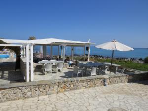 a patio with tables and chairs and an umbrella at Blue Beach Villas Apartments in Stavros