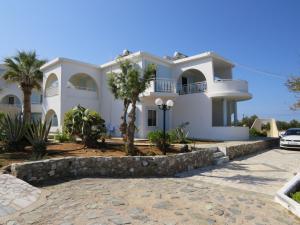 a white house with palm trees in front of it at Blue Beach Villas Apartments in Stavros
