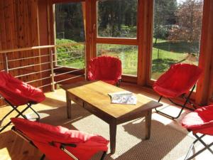 Habitación con 4 sillas rojas y mesa de madera. en La Clé des Champs, en Grazac