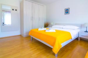 a bedroom with a large bed with an orange blanket at Apartments Nicole in Pula