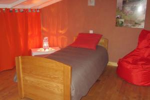 1 dormitorio con cama de madera y almohada roja en La Clé des Champs, en Grazac