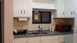 a kitchen with a sink and a microwave at Lee's comfort house in Chalan Kanoa