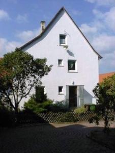 une grande maison blanche avec un arbre en face dans l'établissement Gästehaus Eichwald, à Neuenbürg