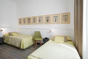 een kamer met 2 bedden en een stoel en foto's aan de muur bij Hotel Bernina in Milaan