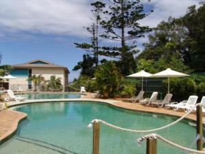 a large swimming pool with chairs and umbrellas at Aqualuna Apartments in Coffs Harbour