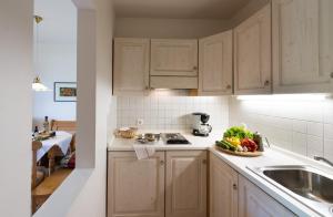 a kitchen with white cabinets and a plate of vegetables at Residence Perwanger in Völs am Schlern +28 photos