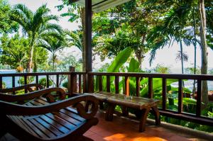 a porch with two benches and a table and trees at Samed Villa Resort in Ko Samed
