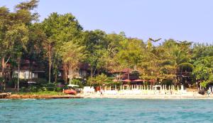 a beach with white chairs and umbrellas on it at Samed Villa Resort in Ko Samed