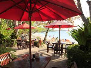 a group of tables and chairs with red umbrellas on the beach at Samed Villa Resort in Ko Samed