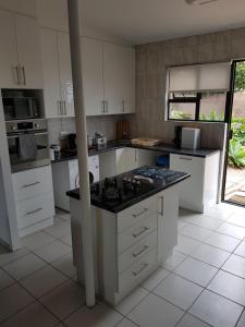 a kitchen with white cabinets and a black counter top at Stukkie Cottage in Hermanus