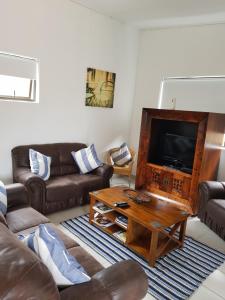 un soggiorno con divani, TV e tavolo di Stukkie Cottage a Hermanus