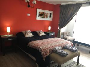 1 dormitorio con 1 cama con paredes rojas en Casa Patagónica Los Frutales en El Calafate
