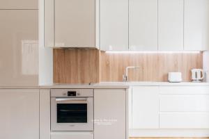 a kitchen with white cabinets and a sink and an oven at Apartament 3 - Bliżej Zdroju in Polanica-Zdrój