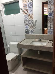 a bathroom with a sink and a toilet and a mirror at Pousada Solar Dos Carneiros in Praia dos Carneiros