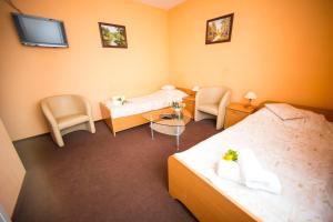 a hotel room with two beds and a table and chairs at Hotel Roko in Warsaw