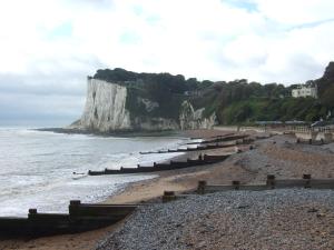 uma praia rochosa com um grande penhasco na água em Hillview em Saint Margaretʼs at Cliffe