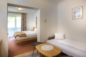 una camera d'albergo con due letti e un tavolo di Alpenhotel Badmeister a Flattach