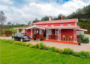 a red house with a car parked in front of it at Teanest Nightingale by Nature Resorts and Stays in Kotagiri