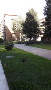 a grassy area with a sidewalk and trees and a building at Appartamento 500mt stadio San Siro in Milan