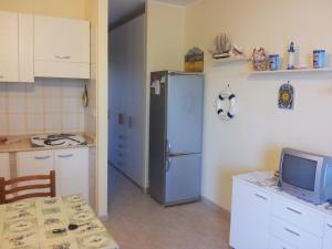 a kitchen with a refrigerator and a table with a television at HOME HOLIDAY PINO&FABIANA in San Vito lo Capo