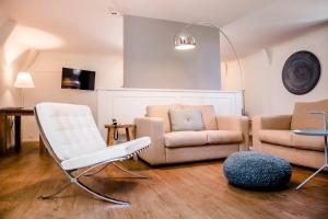 a living room with a white chair and a couch at Kasteeltje Hattem in Roermond