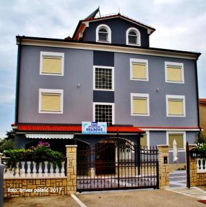 a blue house with a black fence in front of it at Apartmani Krajnović in Fažana