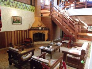 a living room with a staircase and a fireplace at Hotel Pousada Boa Montanha in Monte Verde