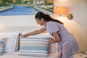 a woman putting a pillow on a bed at Hotel Eden in Cinquale