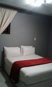 Un dormitorio con una cama con una manta roja encima. en Central Lodge Hotels, en Johannesburgo